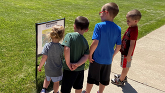 four children reading a storywalk story on a path